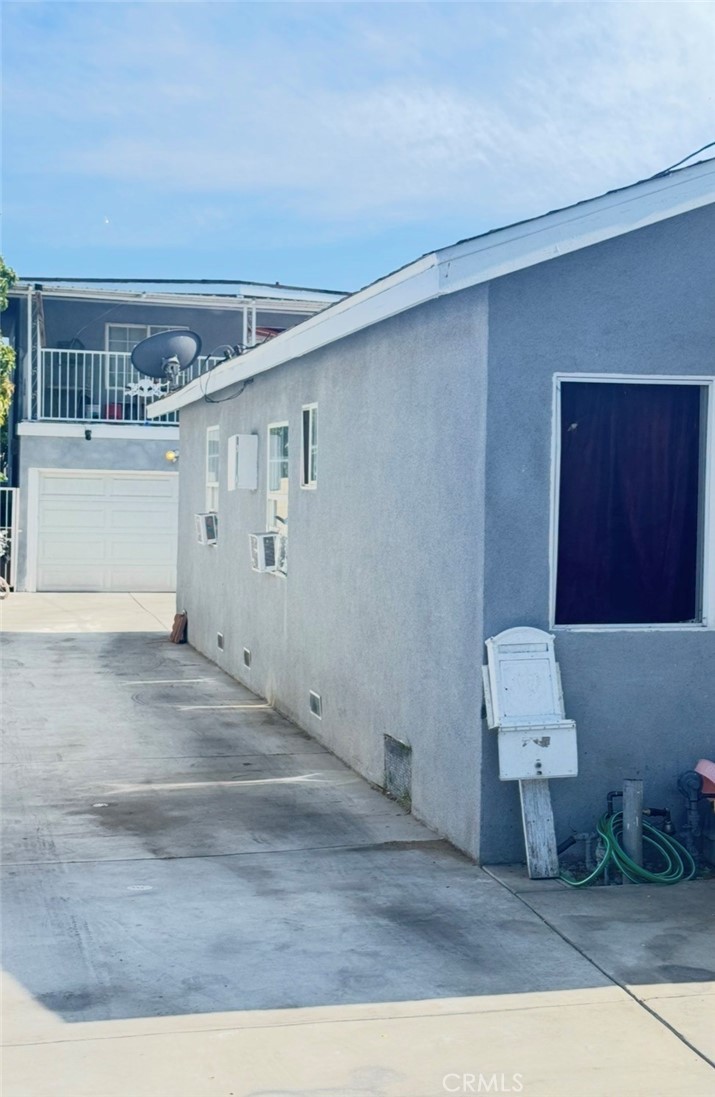 The long concrete driveway running down the side of the front unit toward the white garage door and the two-story rear unit at the back of the lot