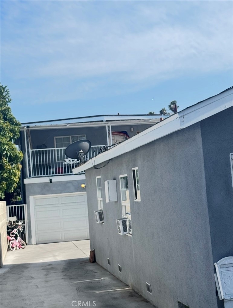 View up the driveway to the two-story rear unit at 4132 W 105th St, with its upstairs balcony, white two-car garage door, and children's bikes parked alongside